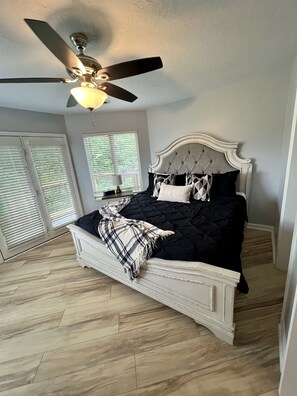 A bedroom with a bed, ceiling fan, and window blinds.