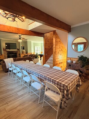 Un espace repas avec une longue table, des chaises blanches et une nappe à carreaux.