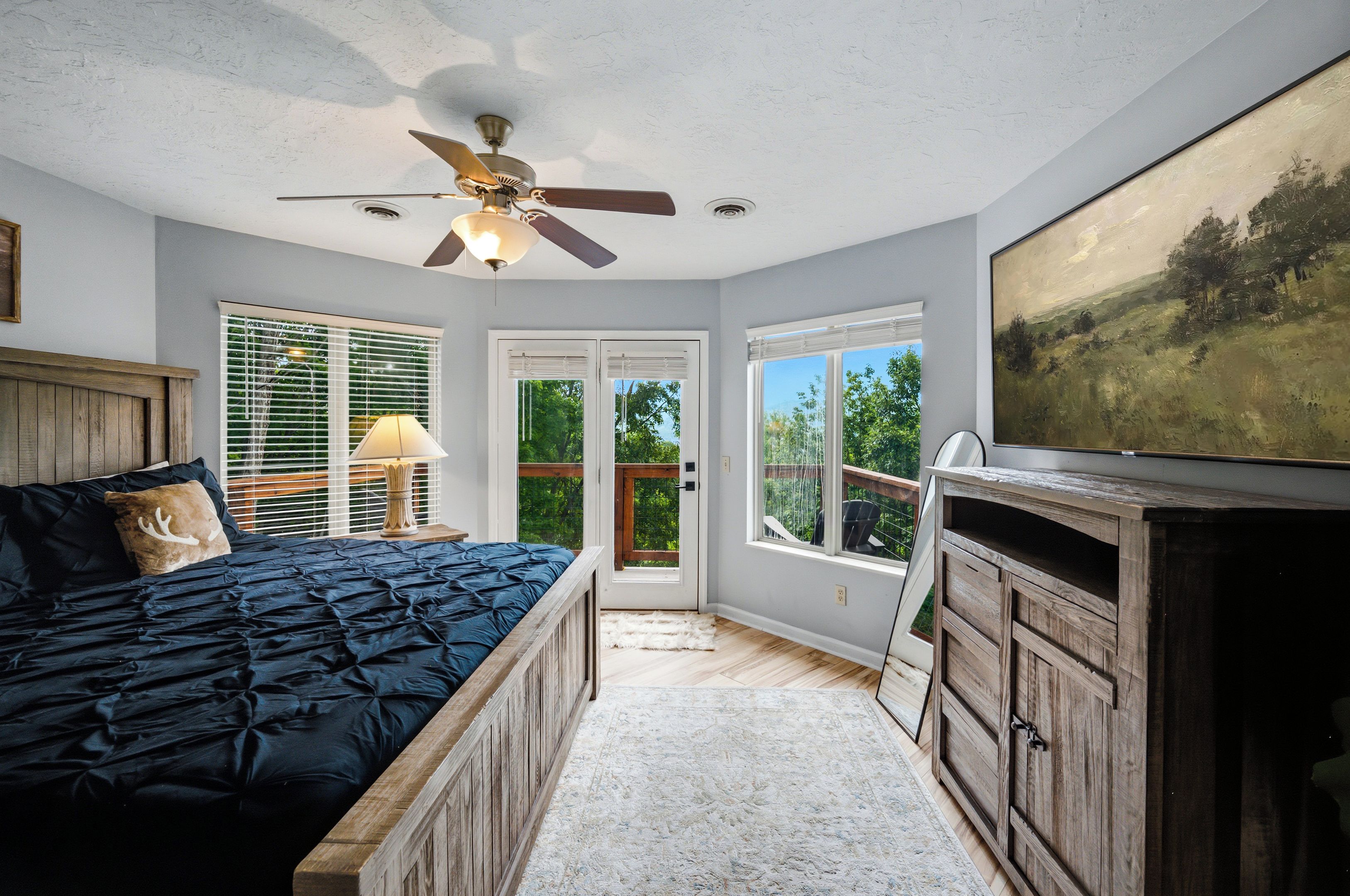 Ein Schlafzimmer mit einem Bett, einem Deckenventilator, einem Bild und Blick durch die Tür.