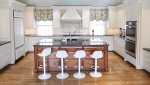 A spacious kitchen with a large island, white cabinetry, and a wooden floor. - Fabulous 4-bedroom villa in tranquil Caves Valley area in Baltimore County MD (Owings Mills)