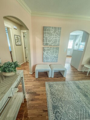 A spacious room with wooden flooring, a bench, a rug, and wall art. - The Pink B • Walk to Square •Airship•Crystal Bridges • MTB Trails (Bentonville)