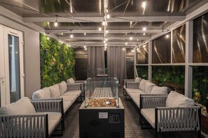 Moderni sisätilalounge, jossa on lasinen sohvapöytä, valkoiset, pehmustetut sohvat ja vihreä, pystysuora viherseinä.
