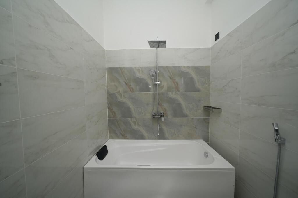 A modern bathroom with a freestanding bathtub, a showerhead, and a handheld shower attachment.
