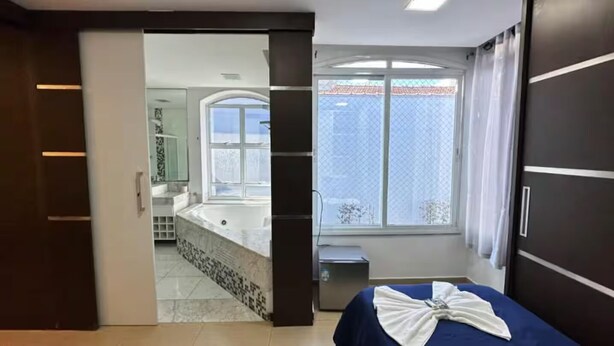 Ein Schlafzimmer mit Bett, einem Fenster mit Aussicht, einem Badezimmer mit Badewanne und einer Schiebetür.