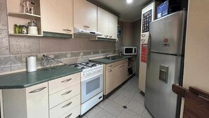 Una cucina compatta con fornello a gas, forno, microonde e frigorifero.