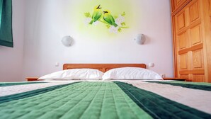 A neatly made bed with a green and white bedspread, a wooden headboard, and a wall-mounted light fixture. - Sea Side Moretti Near Vodice & Beach (Vodice)