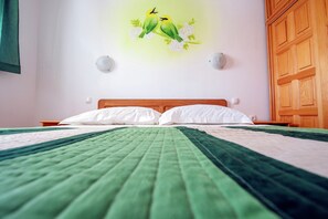 A neatly made bed with a green and white bedspread, a wooden headboard, and a wall-mounted light fixture. - Sea Side Moretti Near Vodice & Beach (Vodice)