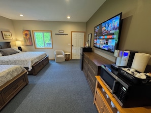 A hotel room with two beds, a TV, a coffee machine, and a small table.