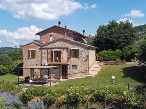 A stone house with a balcony, a patio with outdoor furniture, and a garden with flowers. - Casa dei Nonni by Interhome (Panicale)