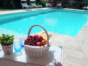 A poolside table with a fruit basket, a potted plant, and a glass. - Casa dei Nonni by Interhome (Panicale)