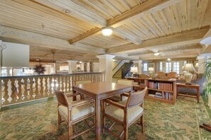 A spacious room with a high ceiling, wooden beams, a dining table with chairs, a bookshelf, and a staircase leading to another level. - The Palm Leaf Suite on Palm Beach Island (Palm Beach)