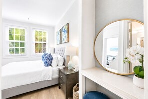 Une chambre à coucher avec un lit, une table de chevet, une lampe et un miroir.