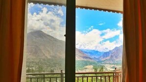 Habitación con vistas a montañas a través de una ventana con cortinas.