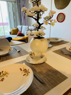 Een eettafel gedekt met borden, een kopje en een vaas met bloemen.