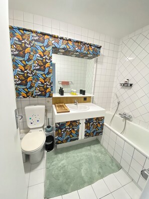 Un baño con inodoro, lavabo, espejo y bañera.