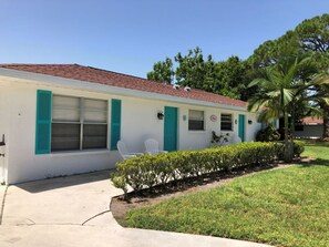 A single-story building with a red-tiled roof, white walls, and green shutters. There is a small front yard with a hedge and a palm tree. - Areas Best Value - Private - Near all attractions- Secure and Immaculately Clean (Nokomis)