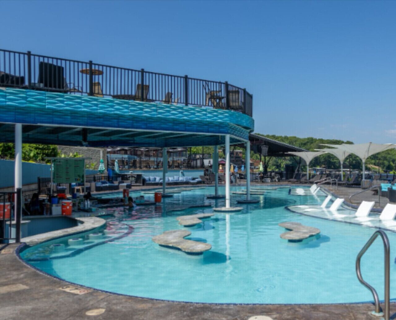 A swimming pool with lounge chairs and a covered area.