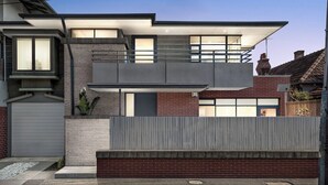 Et moderne hus med to etager, fladt tag, store vinduer og en garage.