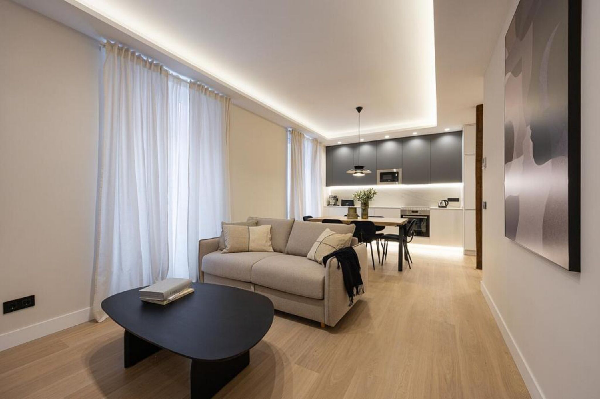 A modern living room with a sofa, a coffee table, and a dining area with a table and chairs.