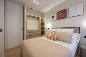 Une chambre à coucher avec un lit, des tables de chevet, une armoire et des œuvres d’art accrochées au mur.