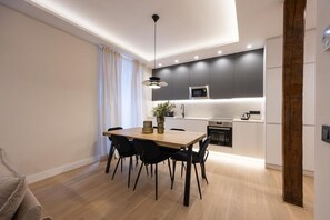 Eine moderne Küche mit Essbereich, ausgestattet mit einem Holztisch, schwarzen Stühlen und einer Pendelleuchte.