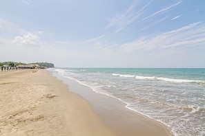 Ein Strand mit sandigem Ufer, wenigen Personen und blauem Himmel.