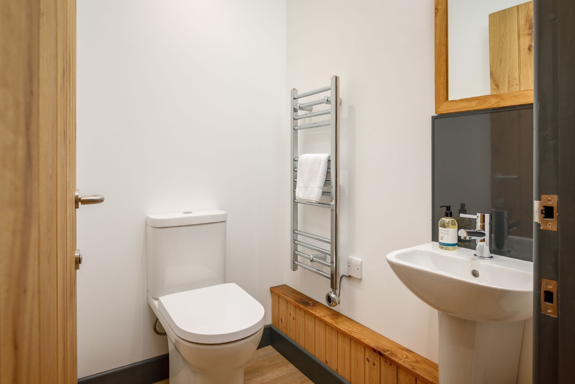 Une petite salle de bain moderne comprenant des toilettes, un porte-serviettes, un lavabo et un miroir.