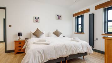 Une chambre à coucher avec un lit, des tables de chevet, une commode et des œuvres d’art accrochées aux murs.