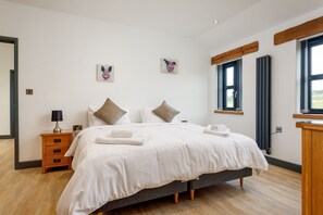 Ein Schlafzimmer mit einem Bett, Nachttischen, einer Kommode und Kunstwerken an den Wänden.