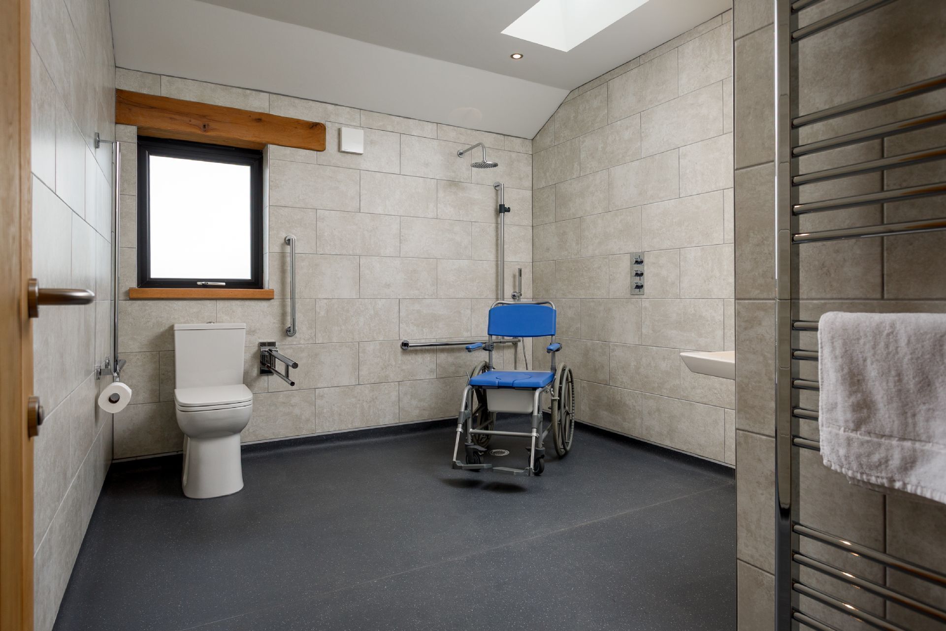 A wheelchair-accessible bathroom with a toilet, shower, and sink.
