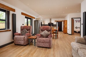 Ein geräumiges Wohnzimmer mit zwei Sesseln, einem Holztisch und einem Sofa.