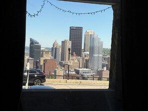 Eine Stadtansicht mit verschiedenen Gebäuden, darunter ein markantes UPS-Gebäude, zu sehen durch ein Fenster mit schwarzem Rahmen und einer Lichterkette.
