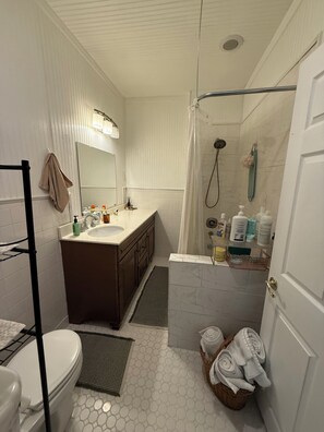 Ein Badezimmer mit Toilette, Waschbecken, Dusche und Handtuchhalter.