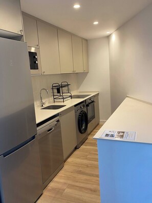 A compact kitchen with a built-in dishwasher, a washing machine, and a sink. - Benalmadena Diana I Tourist Apartment (Benalmádena)