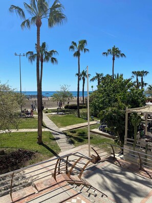 A park with palm trees, a beach in the background, and a gazebo with tables. - Benalmadena Diana I Tourist Apartment (Benalmádena)