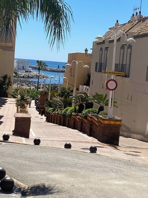 Eine Straße mit einem Verbotsschild, ein Gebäude mit der Beschriftung 'JSM Apartamentos' und im Hintergrund der Blick auf das Meer.
