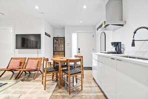 A modern kitchen with white cabinets, a built-in stove, and a coffee maker.