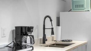 Eine moderne Küche mit Kaffeemaschine, Spüle und Mikrowelle.