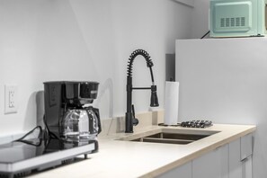 A modern kitchen with a coffee maker, a sink, and a microwave.
