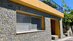 Un bâtiment doté d’une façade en pierre, d’une fenêtre avec des stores et d’une partie supérieure jaune.