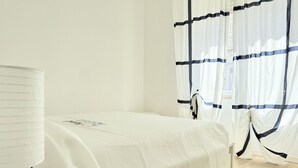 Um quarto com uma cama, uma luminária e cortinas.