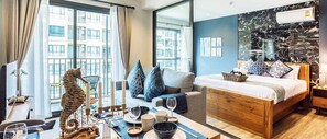 A modern hotel room with a bed, a dining table with candles, a sofa, and a view of the city. - Rain Cha-am Huahin By Sake (Cha-am)