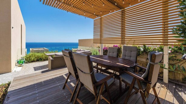 A wooden deck with a table and chairs, overlooking the ocean. - Sea View Panorama | Green Coast 2BR Patio Retreat by PikHost (Palasë)