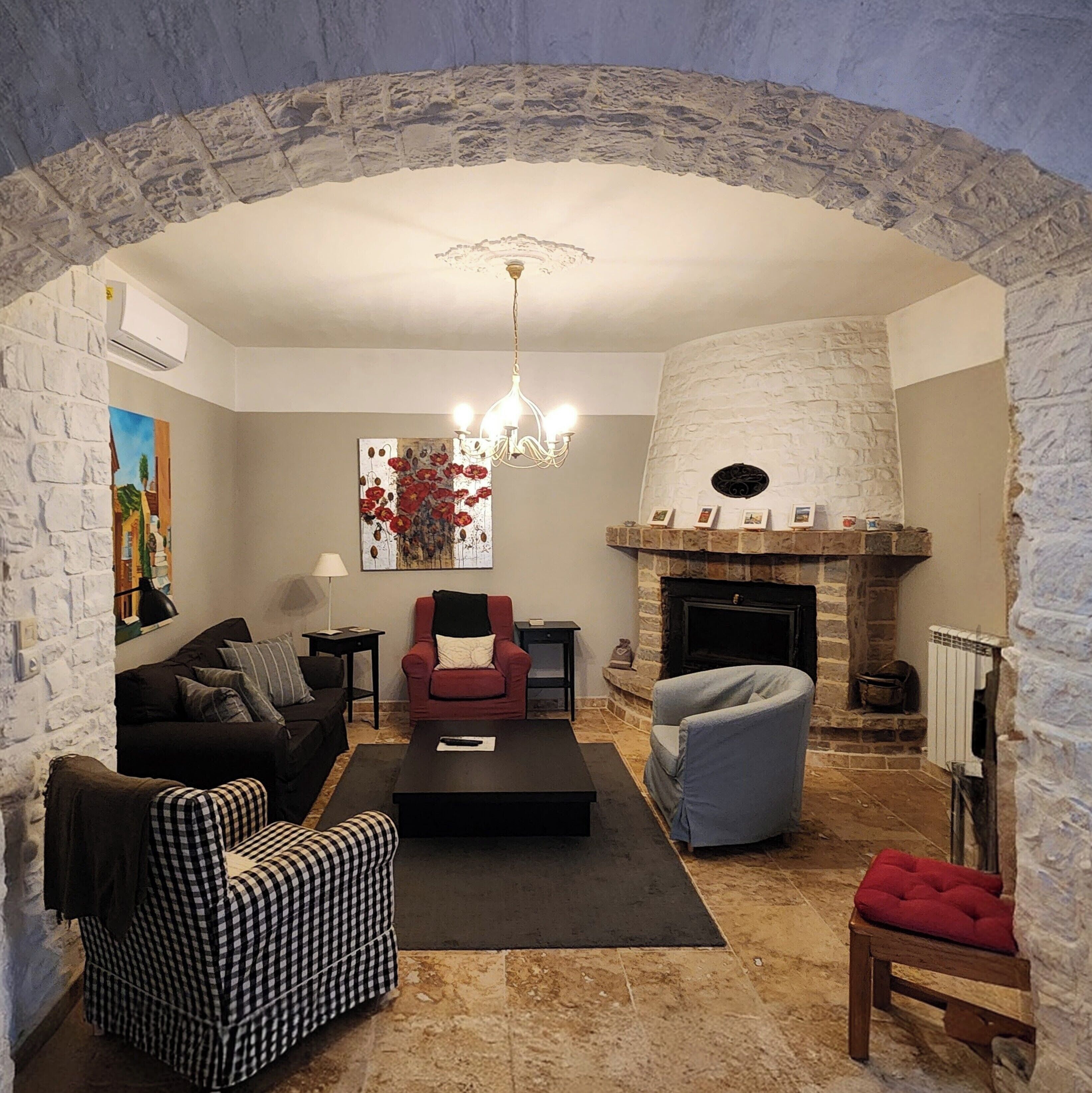 Een woonkamer met een stenen openhaard, een bank, een fauteuil en een salontafel.