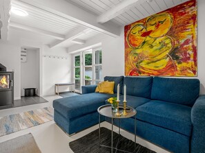 Ein modernes Wohnzimmer mit einem blauen Sofa, einem Kamin und einem großen abstrakten Gemälde.