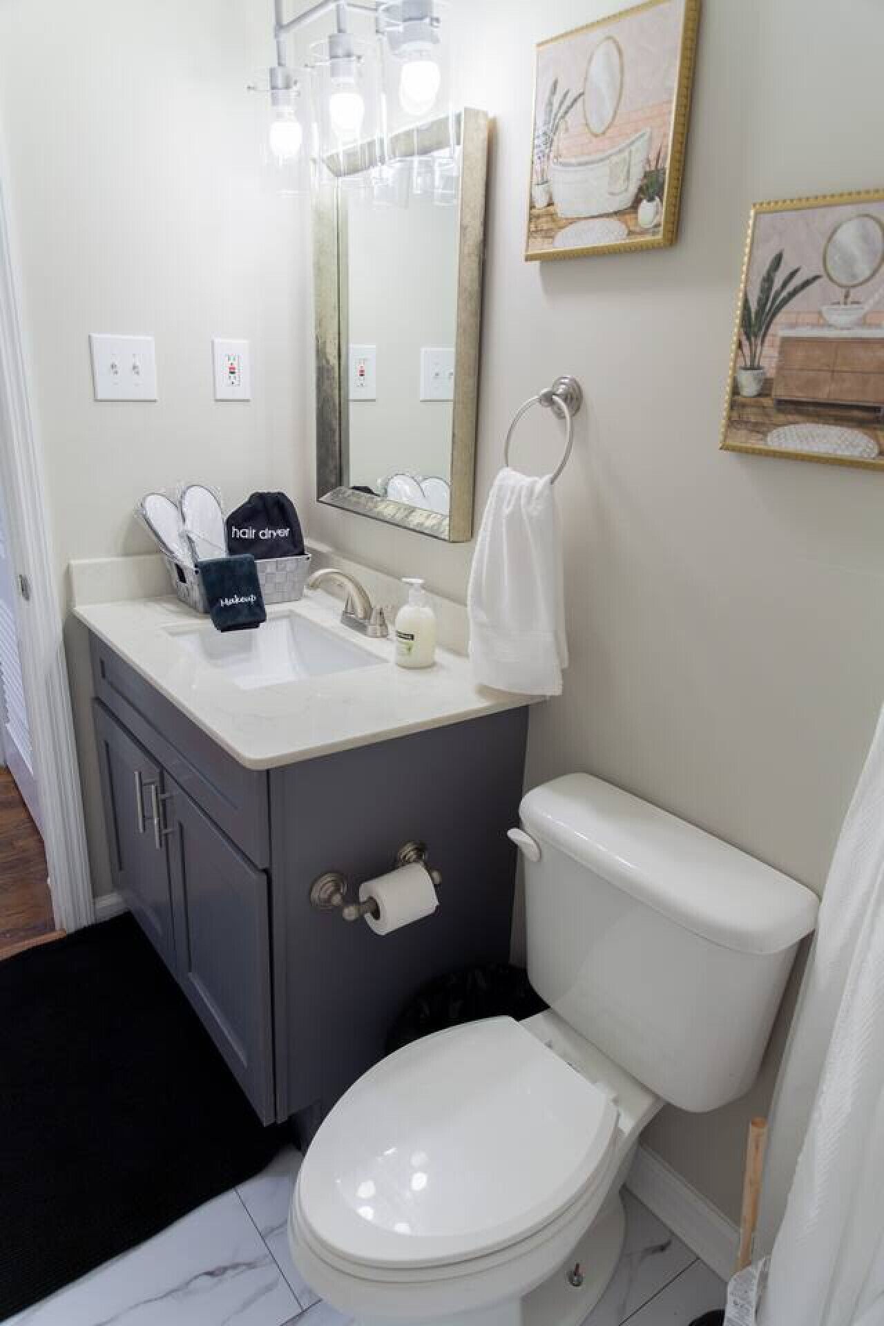 A bathroom with a toilet, sink, mirror, and towel rack.