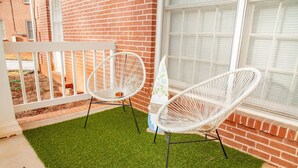 En terrasse med to hvide fletstole, et lille bord og en dekorativ nissefigur.