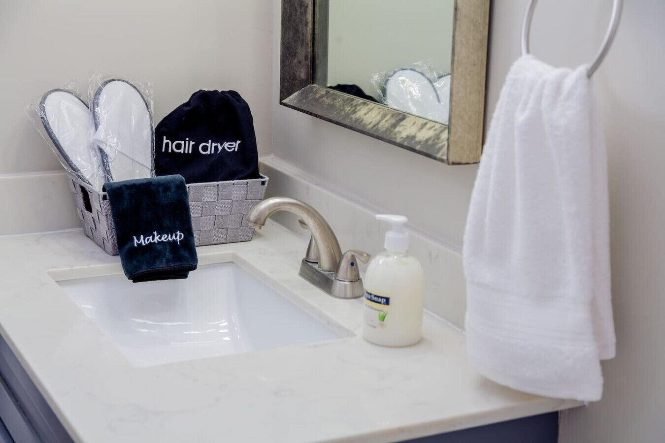 Un baño con lavamanos, secador de pelo, botella de jabón y toallero.