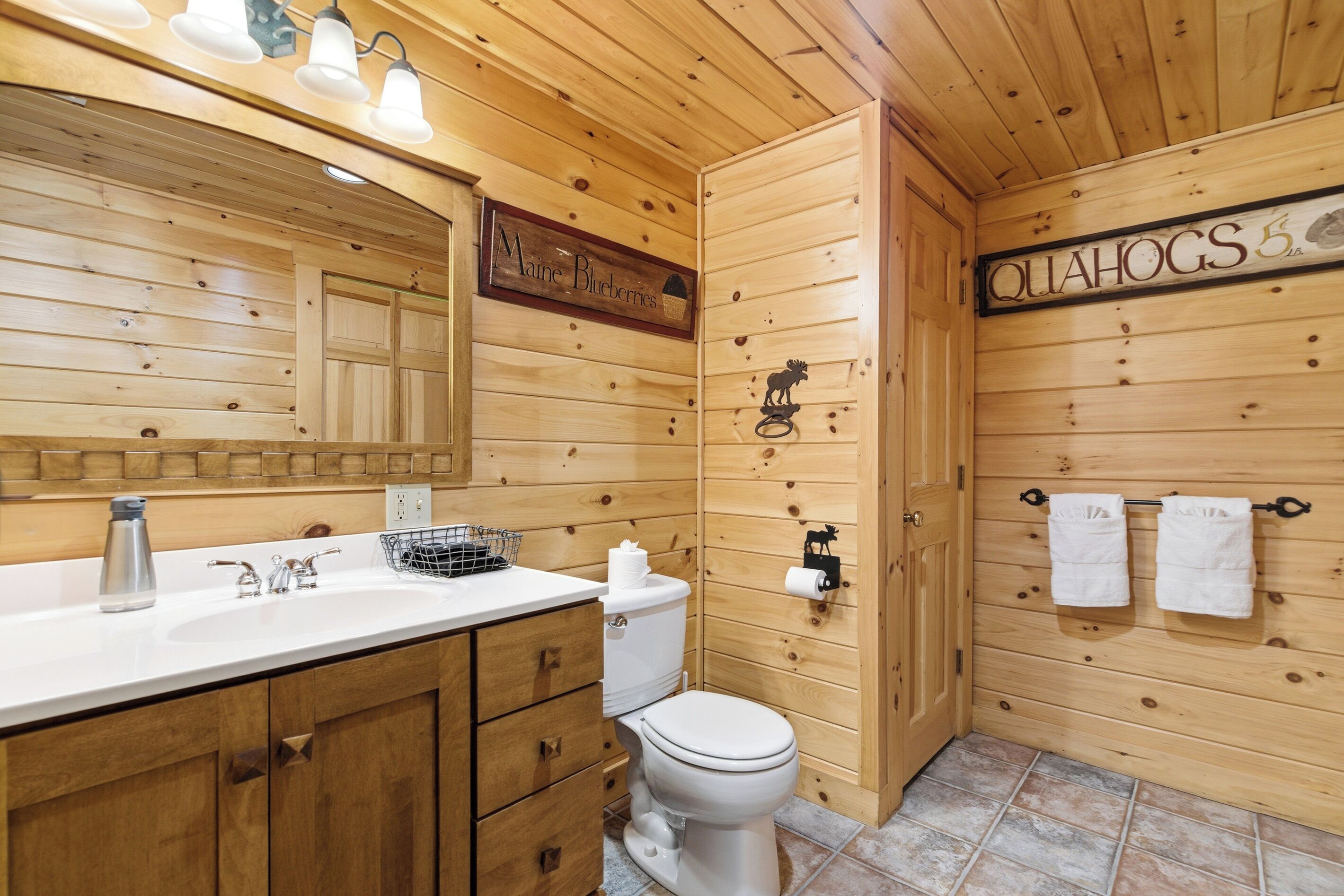 Ein Badezimmer einer Holzhütte mit Waschbecken, Toilette und Handtuchhalter.