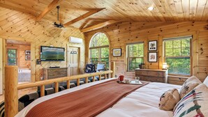 A wooden cabin bedroom with a bed, a TV, a desk, and a window. - Relaxing Newry Chalet | Fire Pit, Hot Tub & Sauna (Newry)